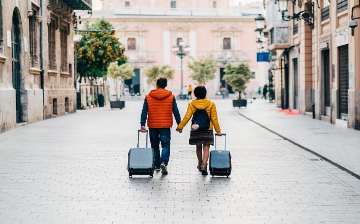 Due viaggiatori con valigia mano nella mano