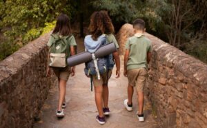Bambini in escursione nel verde durante campi scout in Campania, con zaini immersi nella natura.