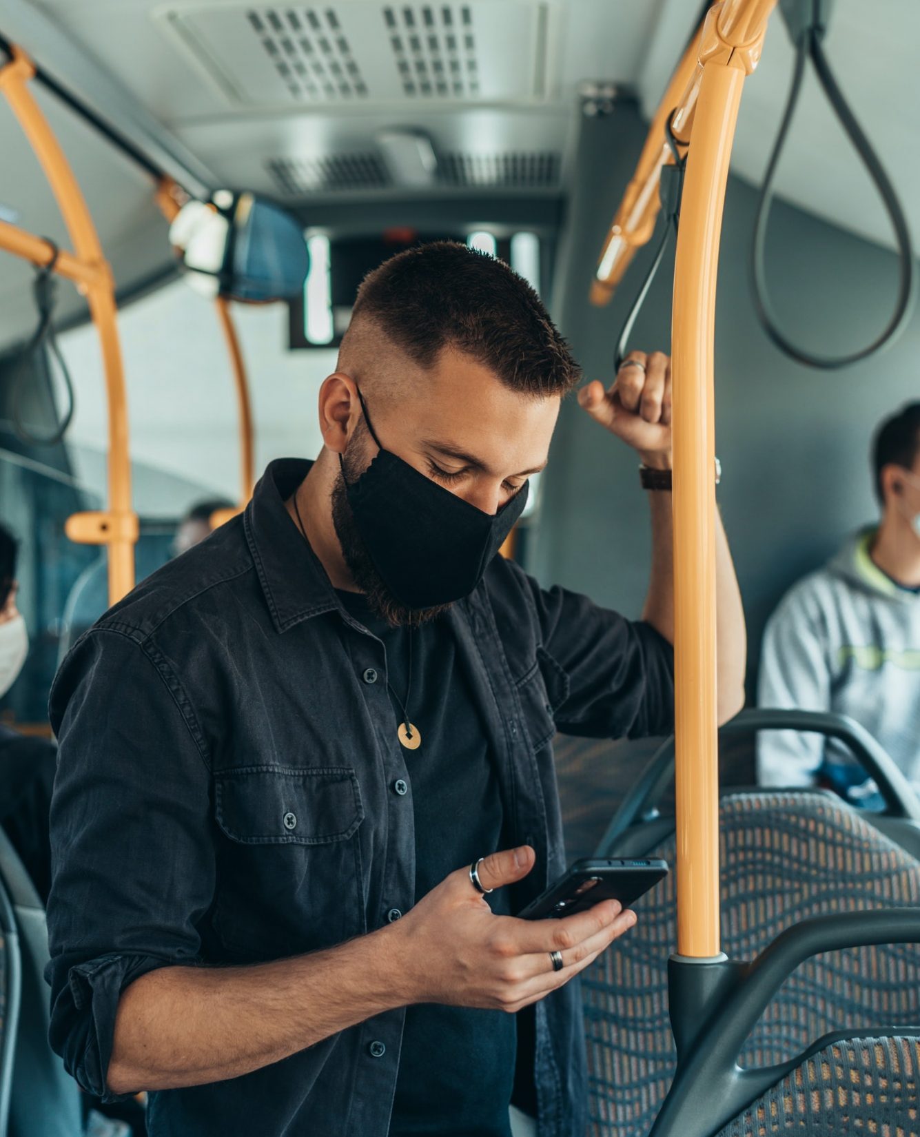 man-wearing-a-protective-mask-and-using-a-smartphone-while-keeping-the-distance-in-the-bus.jpg